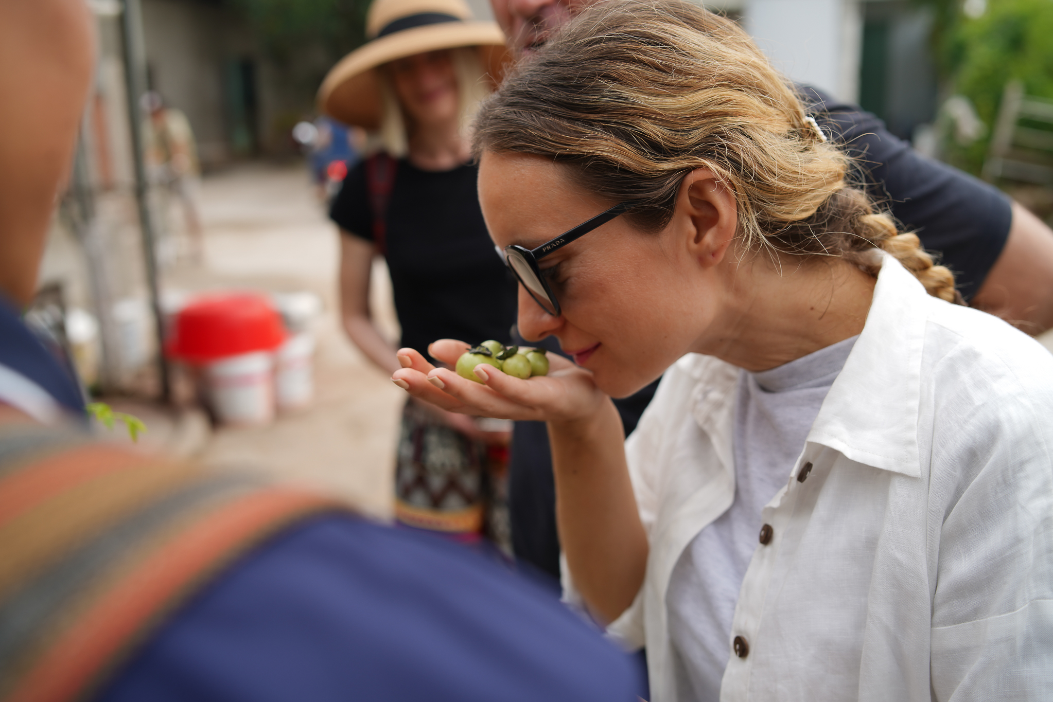 Woman smelling fresh green fruit during a local market experience in the Mekong Delta.