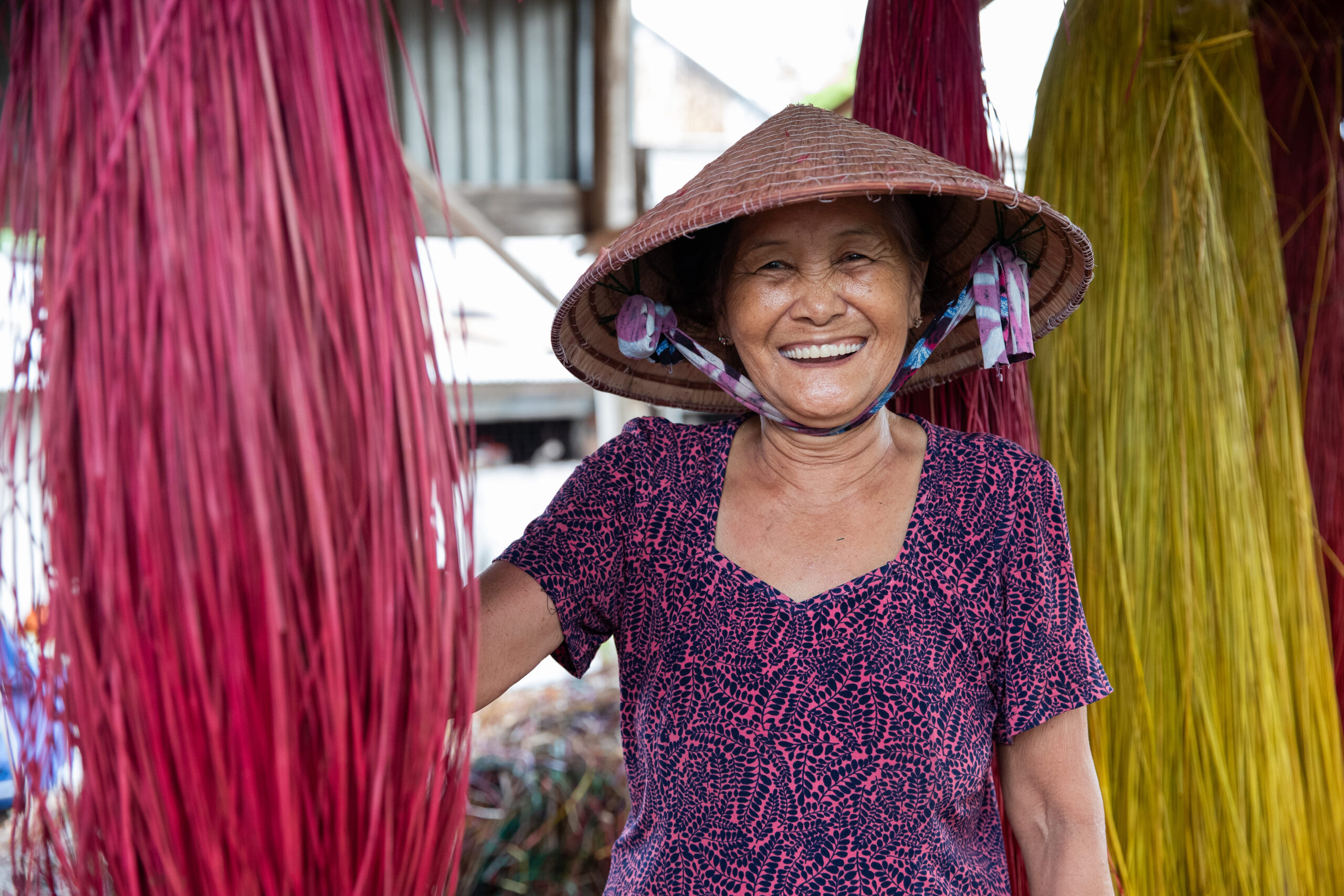 Smiling local artisan wearing a traditional conical hat during a Victoria Mekong Cruises shore excursion